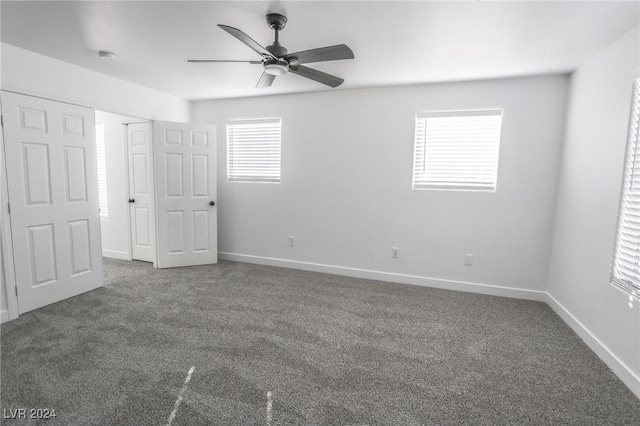 unfurnished bedroom with dark colored carpet and ceiling fan