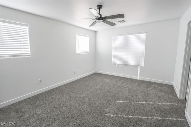 spare room with dark colored carpet and ceiling fan