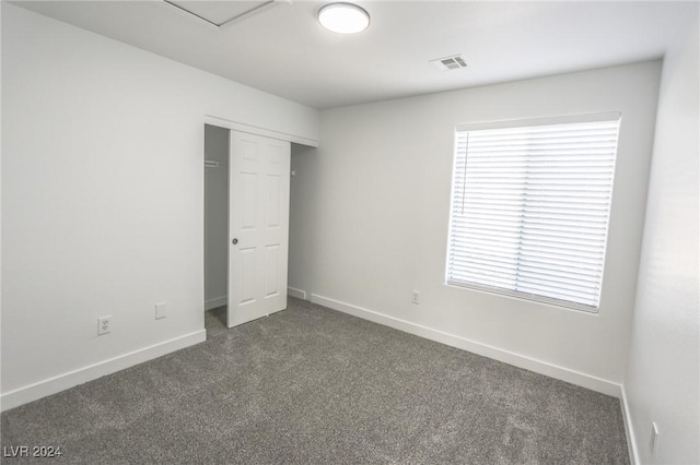 unfurnished bedroom featuring dark colored carpet and a closet