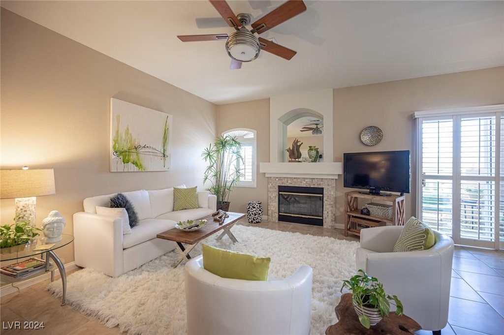 living room with tile patterned flooring, ceiling fan, and a tiled fireplace