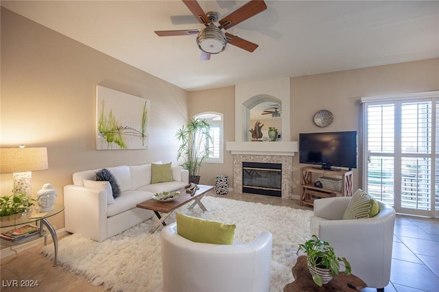 living room with tile patterned flooring, ceiling fan, and a tiled fireplace