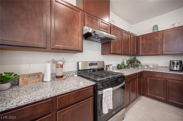 kitchen featuring light stone counters, dark brown cabinets, and stainless steel gas range