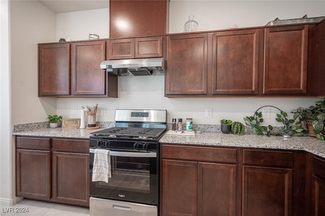 kitchen featuring light stone counters, stainless steel gas stove, light tile patterned floors, and dark brown cabinets