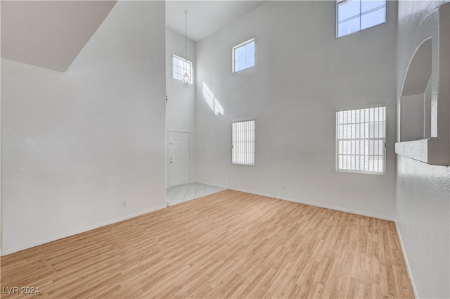 unfurnished room with a towering ceiling and light wood-type flooring