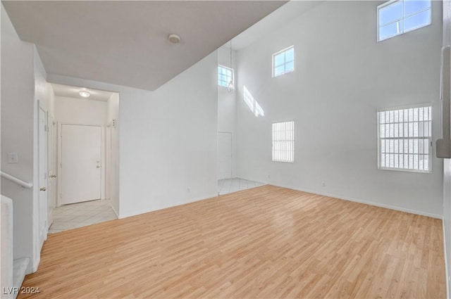 empty room with light wood-type flooring and a high ceiling