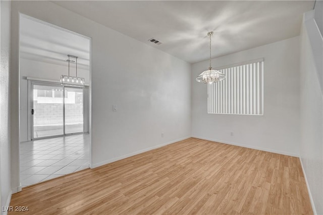 empty room with an inviting chandelier and light wood-type flooring