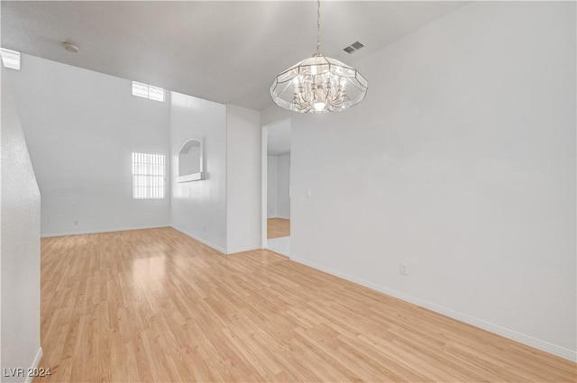 spare room featuring light hardwood / wood-style flooring and a chandelier