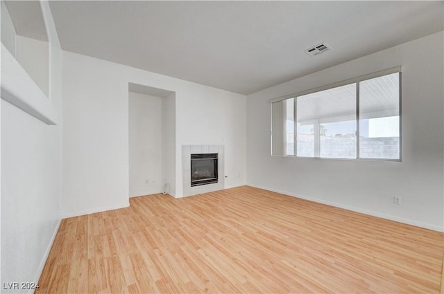 unfurnished living room featuring a tile fireplace and light hardwood / wood-style flooring