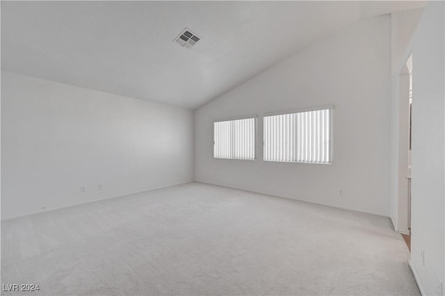 empty room with light colored carpet and vaulted ceiling