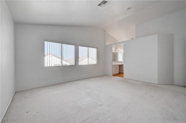 spare room featuring lofted ceiling and light carpet