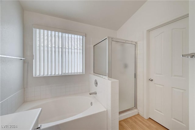 bathroom featuring wood-type flooring, shower with separate bathtub, and vaulted ceiling