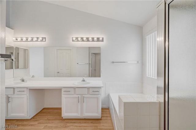 bathroom with a bath, hardwood / wood-style floors, vanity, and vaulted ceiling