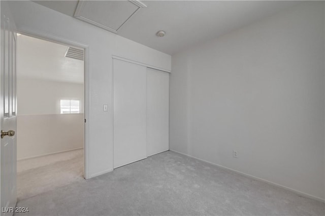 unfurnished bedroom featuring a closet and light colored carpet