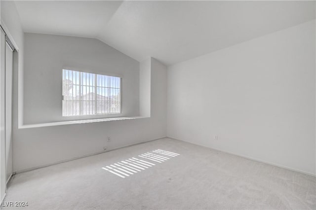 carpeted spare room with vaulted ceiling