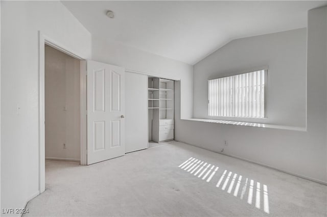 unfurnished bedroom with light carpet, a closet, and vaulted ceiling