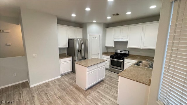 kitchen with white cabinets, sink, light wood-type flooring, appliances with stainless steel finishes, and a kitchen island