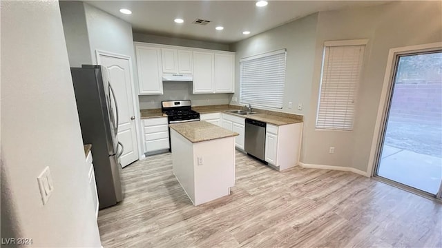 kitchen with sink, a kitchen island, light hardwood / wood-style floors, white cabinetry, and stainless steel appliances