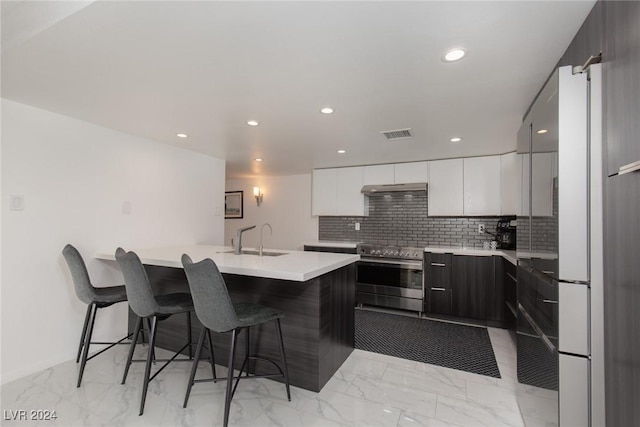 kitchen featuring decorative backsplash, a breakfast bar, sink, white cabinets, and stainless steel electric range oven