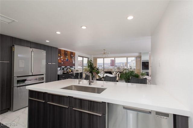 kitchen featuring kitchen peninsula, stainless steel appliances, a notable chandelier, and sink