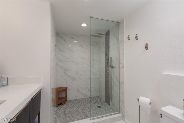 bathroom featuring vanity, toilet, and a tile shower