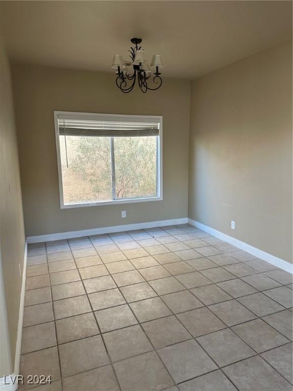 tiled empty room with a notable chandelier