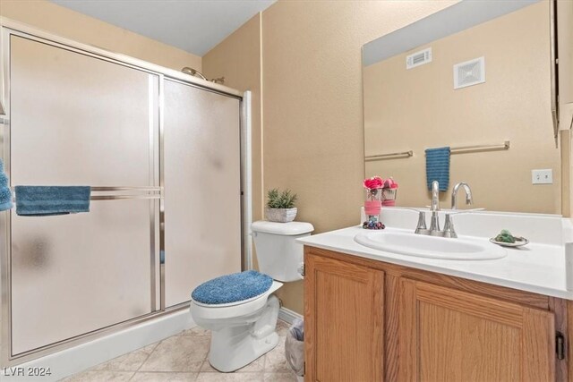 bathroom featuring tile patterned floors, toilet, vanity, and walk in shower