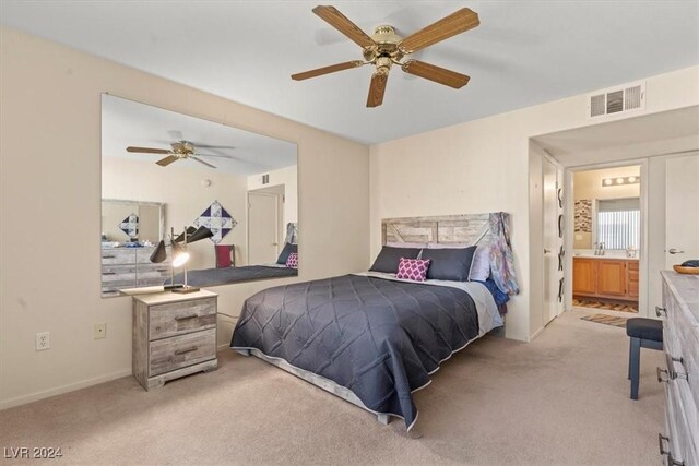 bedroom with ceiling fan, ensuite bathroom, and light colored carpet