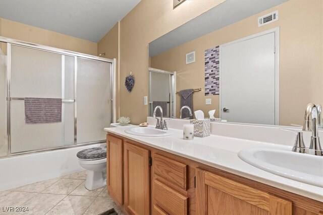 full bathroom featuring tile patterned floors, vanity, bath / shower combo with glass door, and toilet