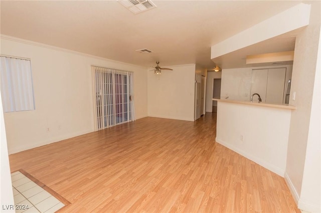 unfurnished living room featuring ceiling fan, light hardwood / wood-style floors, ornamental molding, and sink