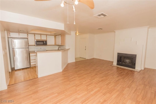 unfurnished living room featuring light hardwood / wood-style floors, ceiling fan, and sink