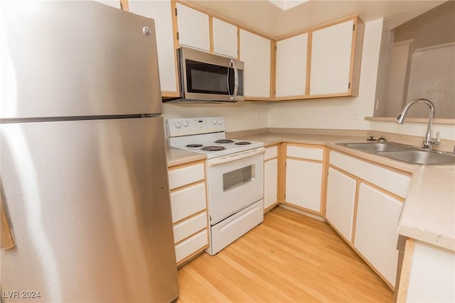 kitchen featuring sink, white cabinetry, stainless steel appliances, and light hardwood / wood-style flooring