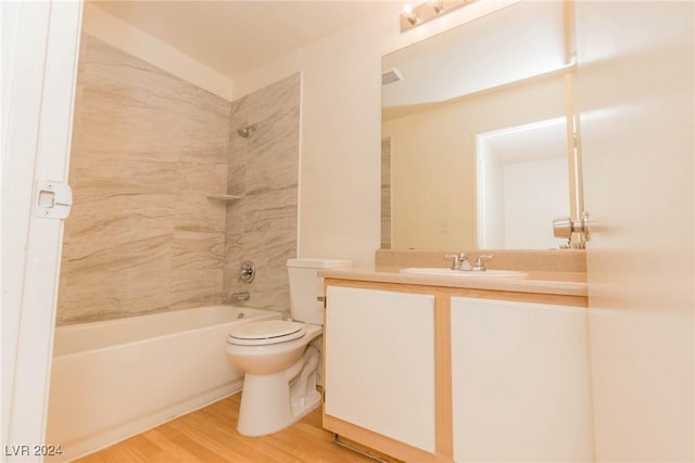 full bathroom featuring hardwood / wood-style flooring, tiled shower / bath combo, toilet, and vanity