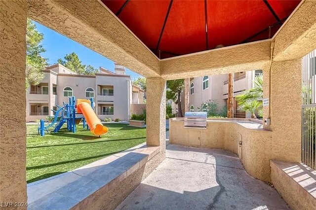 view of patio / terrace featuring a playground, area for grilling, and exterior kitchen