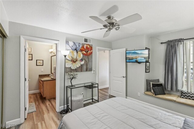 bedroom with ensuite bath, ceiling fan, sink, and light hardwood / wood-style floors