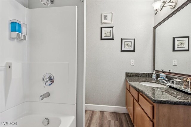 bathroom with bathing tub / shower combination, vanity, and wood-type flooring