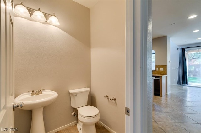 bathroom with tile patterned floors, tasteful backsplash, toilet, and sink