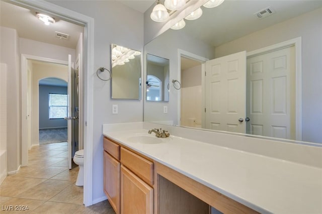 bathroom with tile patterned floors, an inviting chandelier, vanity, and toilet