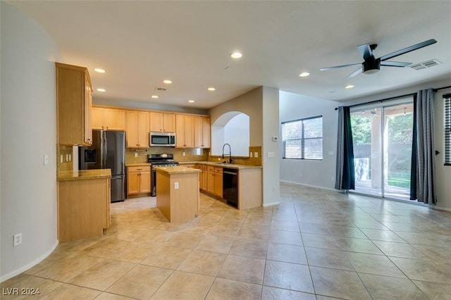 kitchen featuring appliances with stainless steel finishes, ceiling fan, sink, light tile patterned floors, and a kitchen island