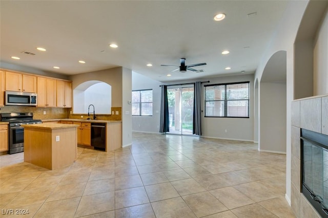 kitchen with sink, ceiling fan, light tile patterned floors, a fireplace, and stainless steel appliances