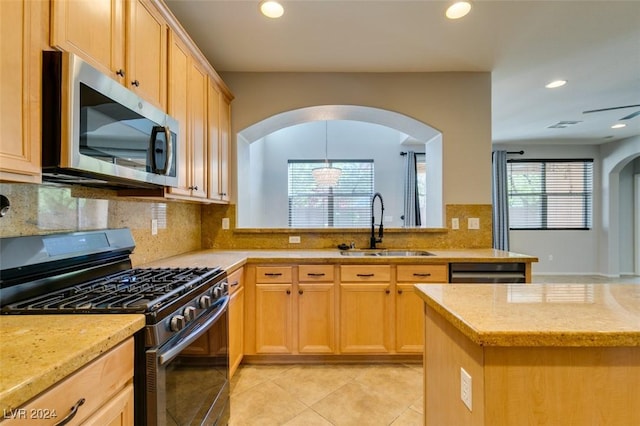 kitchen featuring light stone countertops, sink, light brown cabinets, decorative backsplash, and appliances with stainless steel finishes