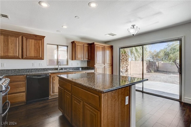 kitchen with sink, dark hardwood / wood-style floors, black dishwasher, stainless steel range with gas stovetop, and a kitchen island