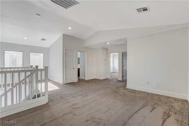 carpeted spare room featuring vaulted ceiling