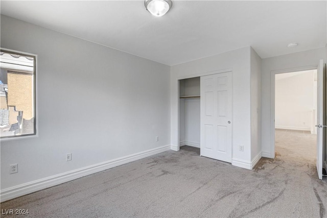 unfurnished bedroom with a closet and light carpet