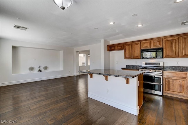 kitchen with a center island, a kitchen breakfast bar, dark hardwood / wood-style floors, and range with two ovens