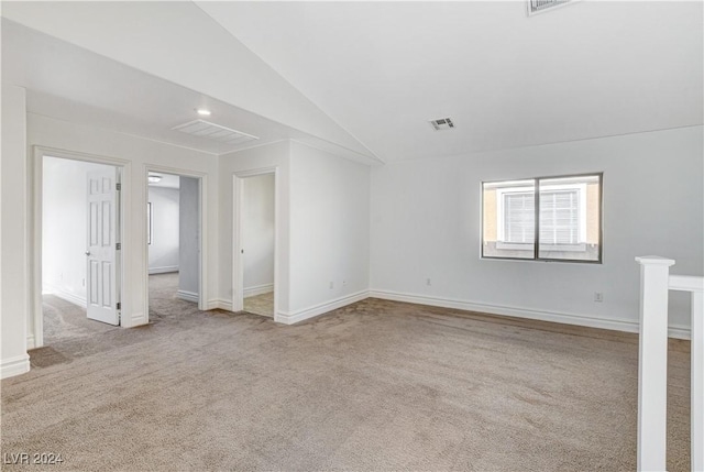 carpeted spare room with vaulted ceiling