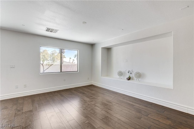 unfurnished room with a textured ceiling and dark hardwood / wood-style flooring