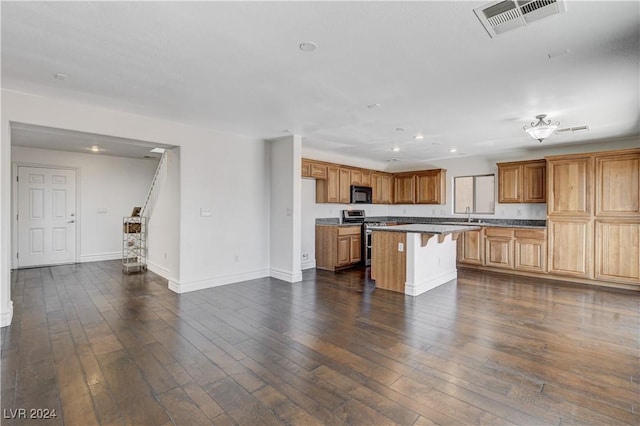 kitchen with dark hardwood / wood-style flooring, a center island, stainless steel range, and a kitchen bar