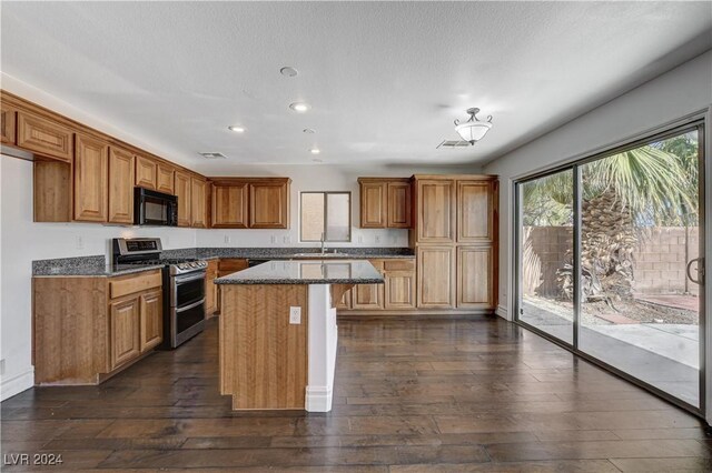 kitchen featuring sink, dark stone countertops, double oven range, a center island, and dark hardwood / wood-style flooring