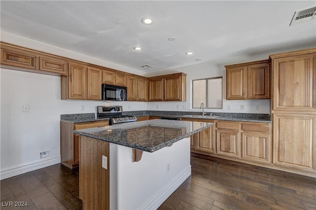 kitchen featuring sink, a center island, stainless steel range, dark hardwood / wood-style floors, and dark stone counters