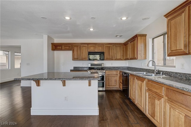 kitchen with sink, a breakfast bar, dark hardwood / wood-style floors, a center island, and black appliances